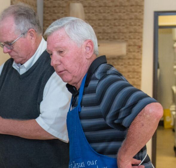 Picture of a wise man in an apron looking wistfully at a table.